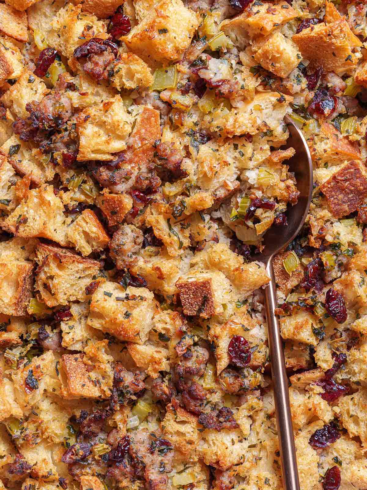 A close-up picture of the finished sausage meat stuffing being scooped up by a golden spoon.