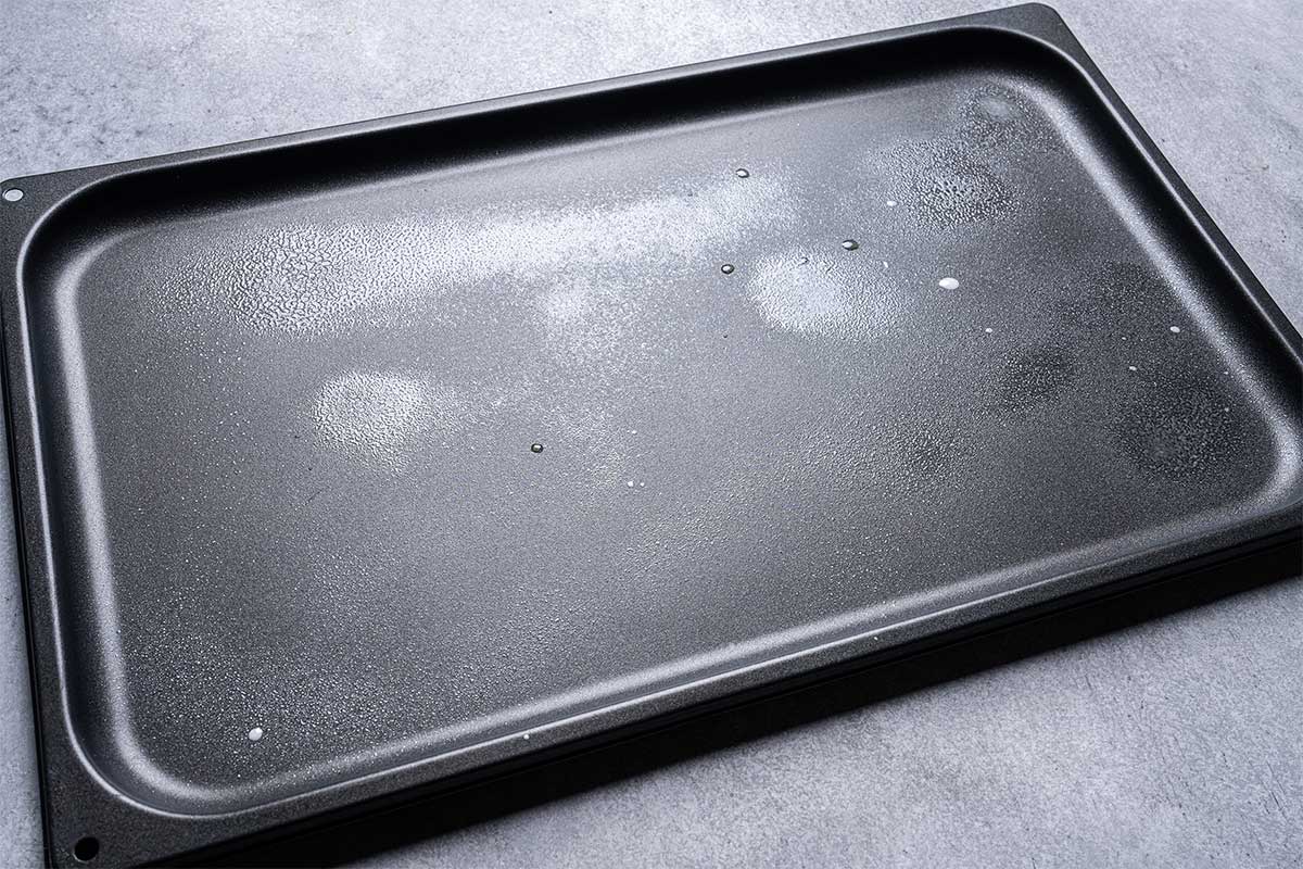 A baking tray lightly sprayed with cooking oil, prepared and ready for arranging potatoes on it.