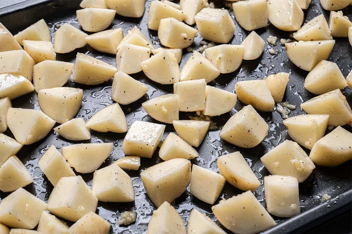 Potatoes arranged on the baking tray in a single layer.