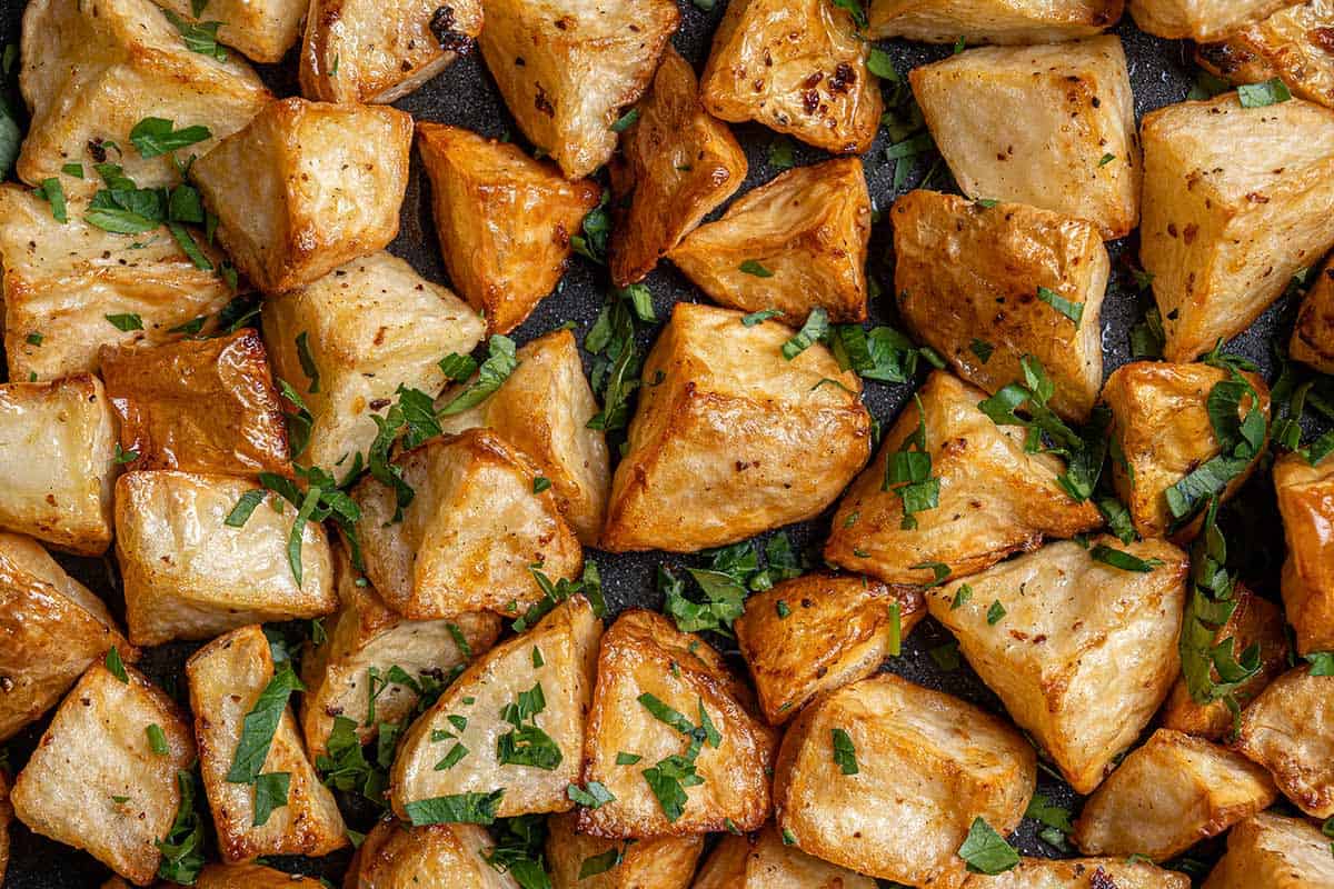 Top view image of roasted potatoes ready to be served, golden and buttery, sprinkled with fresh parsley.