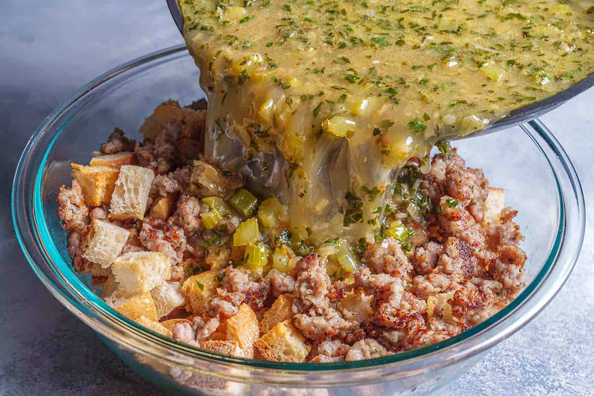 Step 4: The image shows broth being poured over a mixture of bread cubes, sausage, and vegetables in a transparent bowl.