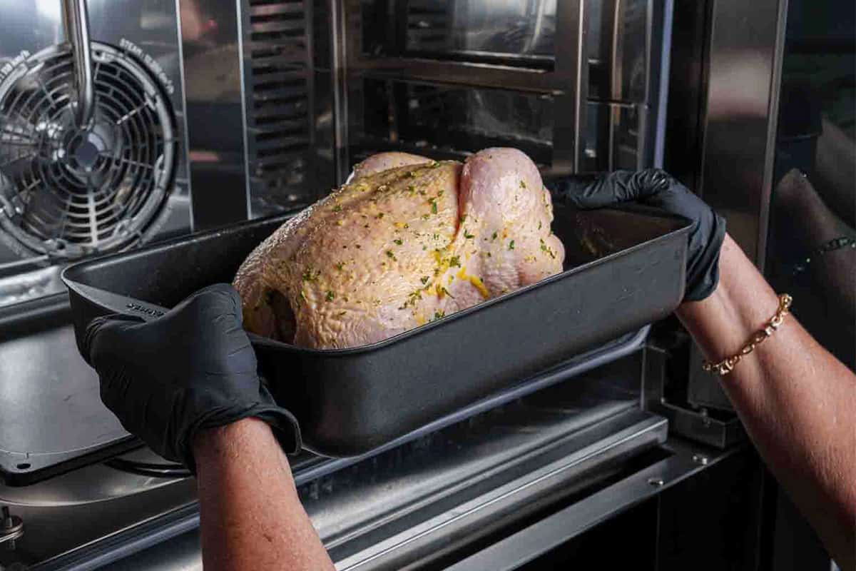 Image showing the chicken placed breast-side up in a baking tray, roasting for 1 hour and 15-20 minutes, with basting halfway through until juices run clear