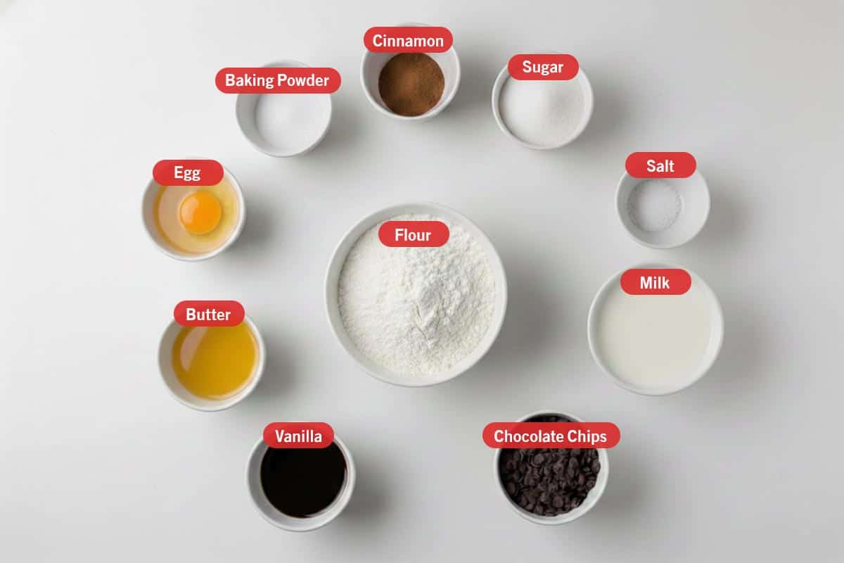 Top shot of ingredients: vanilla, butter, egg, baking powder, cinnamon, sugar, salt, milk, chocolate chips, and flour. - 2