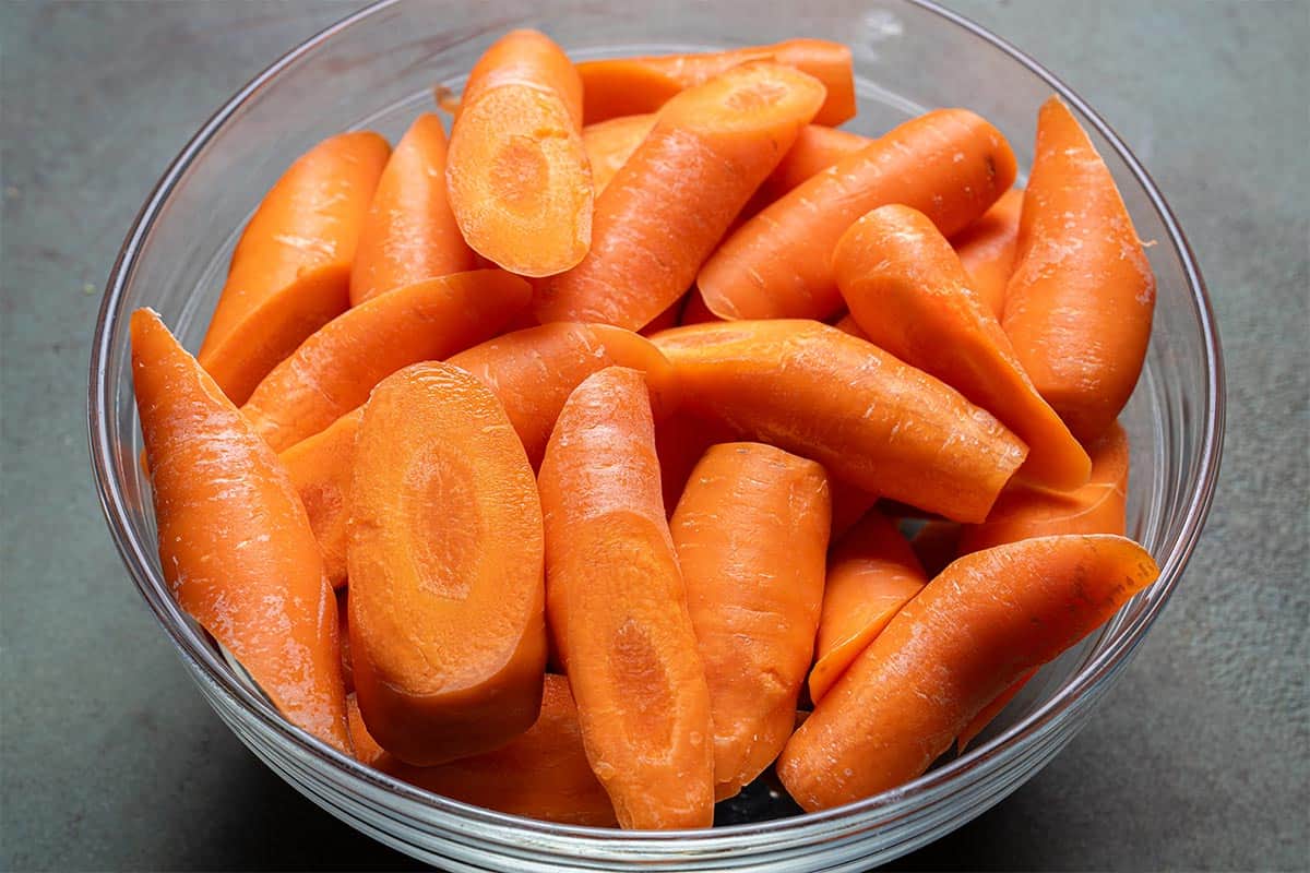 Image of carrots with trimmed ends, cut into thirds, placed in a clear bowl.