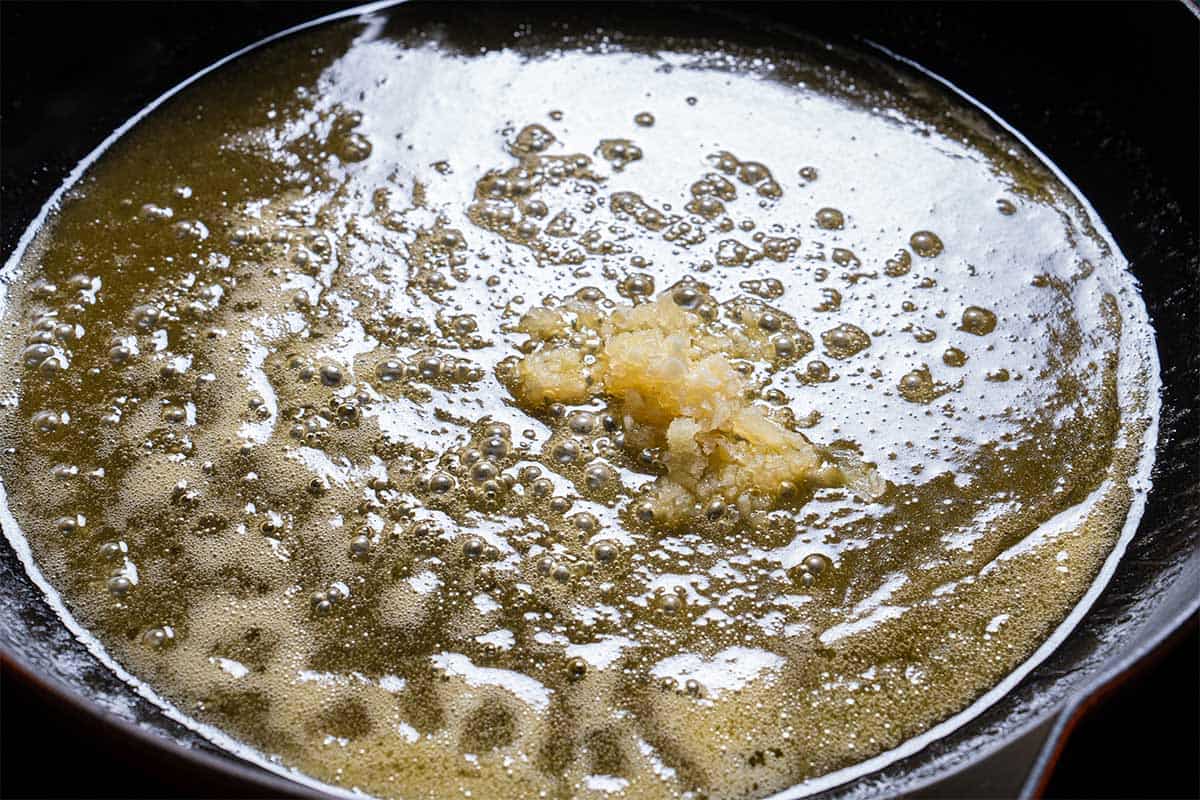 Image of minced garlic added to a skillet with melting butter.