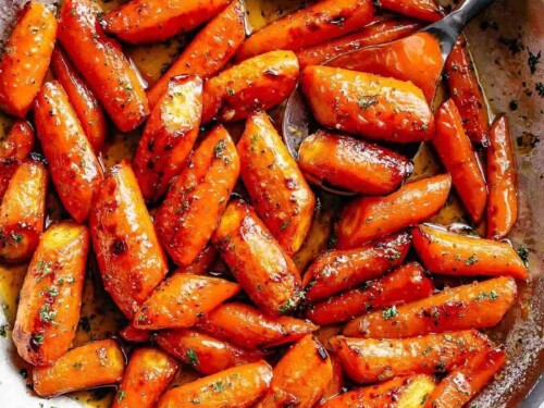 Close-up image of delicious butter-roasted carrots in a pan, garnished with fresh parsley.