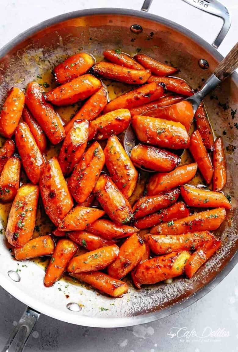 Close-up image of delicious butter-roasted carrots in a pan, garnished with fresh parsley.