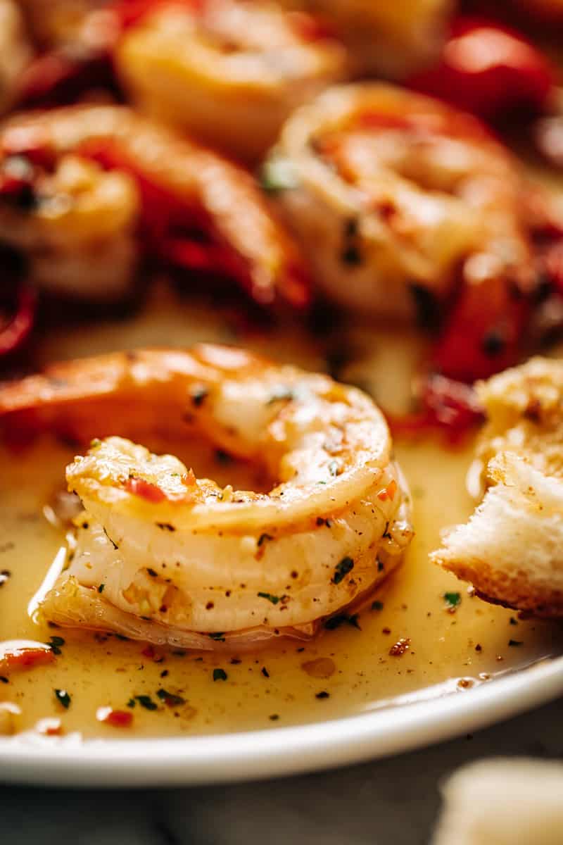 Close up image of a shrimp in a buttery sauce with a few more in the background