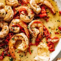 Image of a white plate with Chili Garlic Butter Shrimp in a buttery sauce