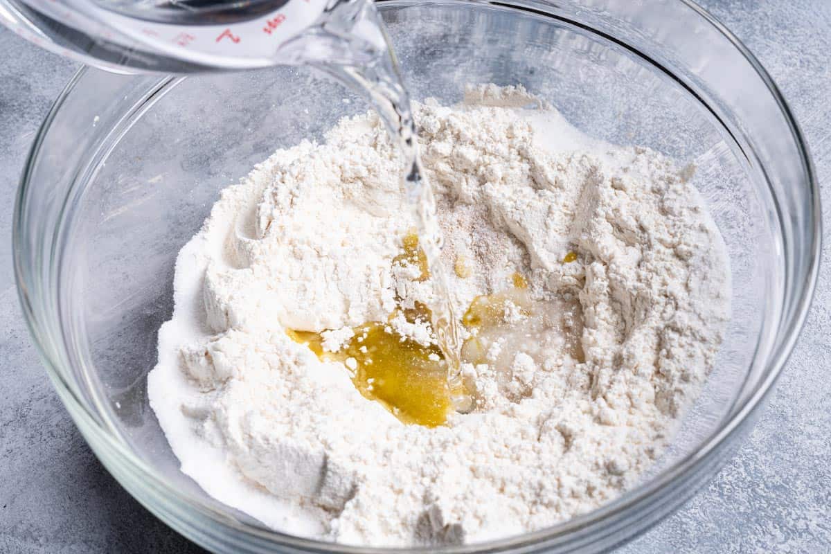 An image of water being added to a clear bowl containing all the ingredients.