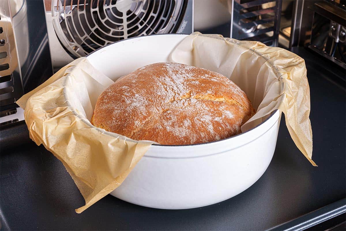 An image of bread still inside a Dutch oven, showcasing a perfectly golden-brown crust.