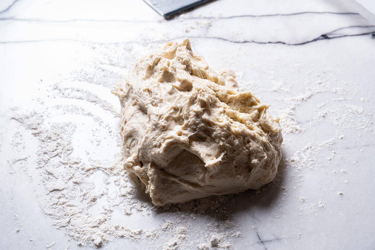 Dough is being scraped off the bowl and placed on the counter.