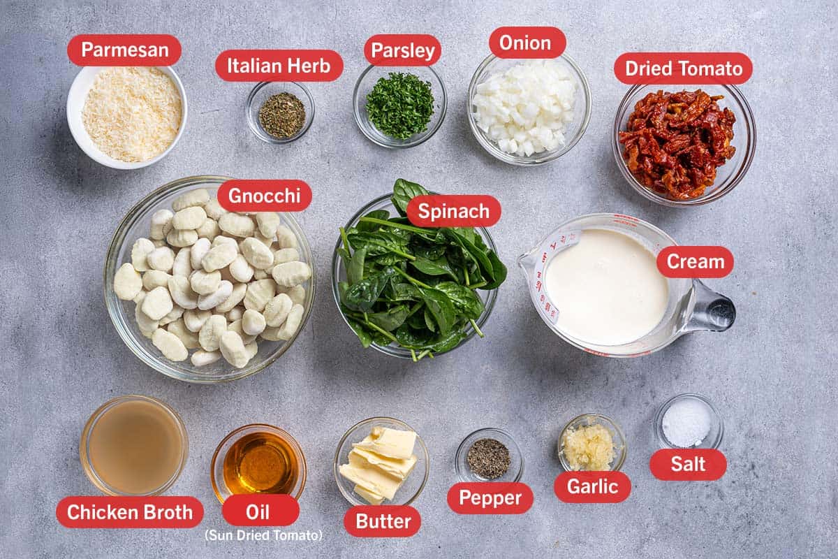 Image of all ingredients needed for the preparation of this recipe, specifically: gnocchi, spinach, cream, chicken broth, oil, butter, pepper, garlic, salt, parmesan, italian herb, parsley, onion, dried tomato.