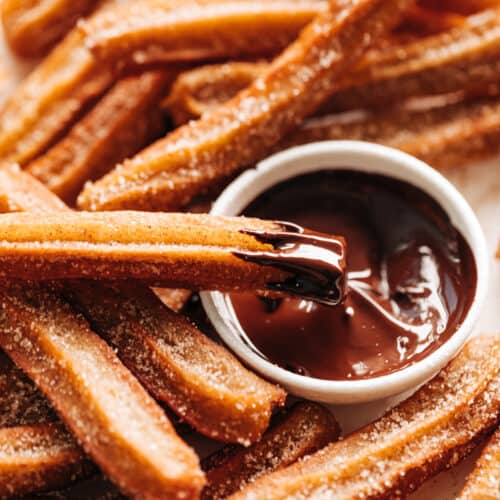 A plate of churros with chocolate dipping sauce.