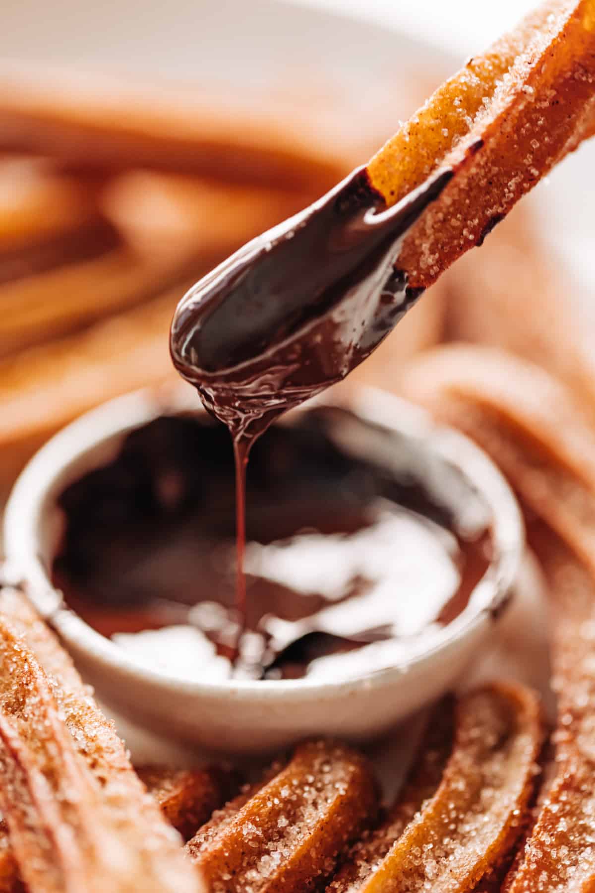 Close-up image of a churro being dipped in chocolate sauce