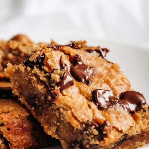 A piece of chickpea banana blondies with melted chocolate chips on a white plate