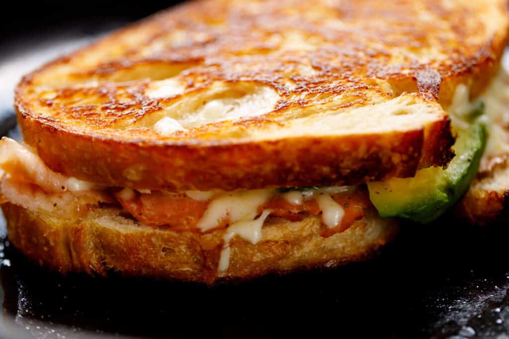 Close up of the side of the grilled cheese in a pan. 