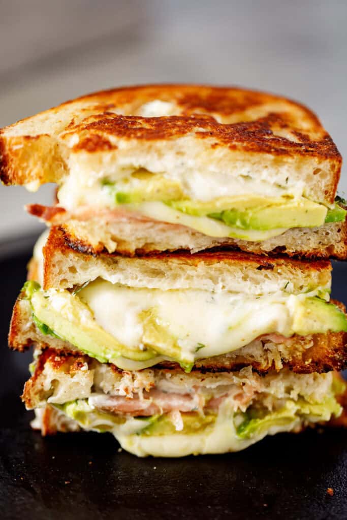 Three halves of the finished salmon and avocado grilled cheese stacked on top of each. 