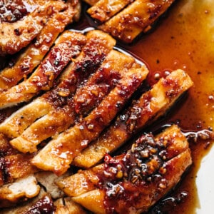 Chicken breast with hot honey butter sauce on a white plate.
