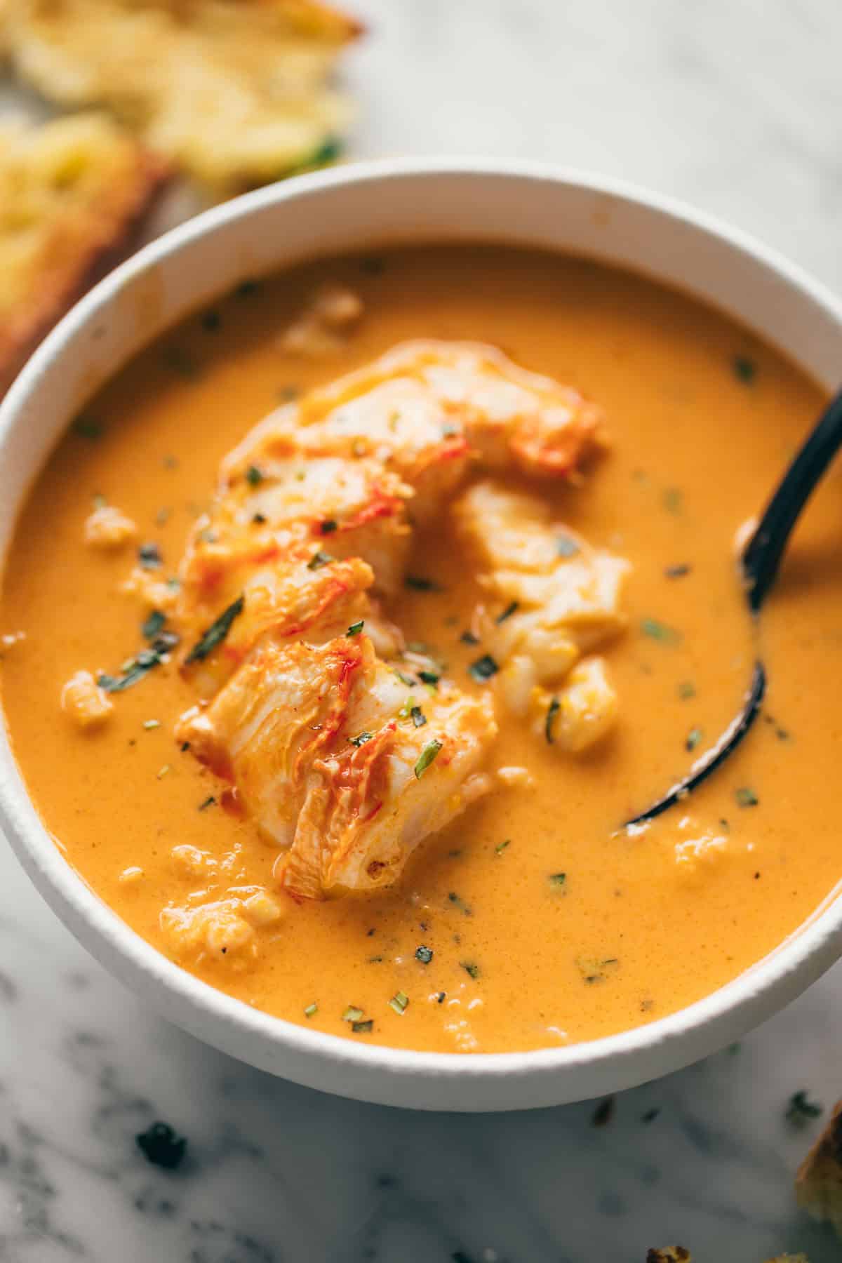 Scrumptious lobster bisque topped with chunks of lobster tail and freshly cut thyme and tarragon, accompanied by a side of toasted bread