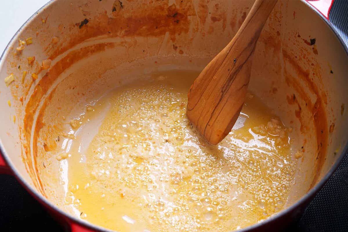 Butter melting in a pan over medium heat with garlic sautéing until fragrant.