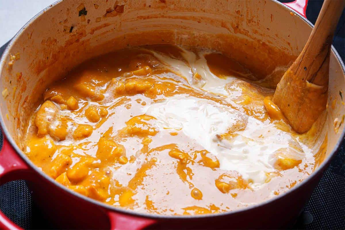 Finished lobster being stirred in the pan before being poured into a bowl.