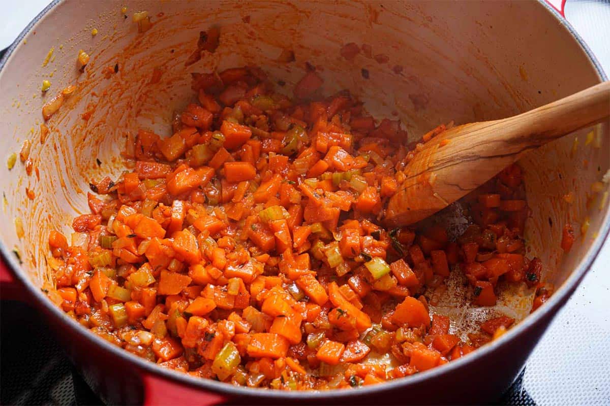 Vegetables being cooked with the addition of tomato paste.