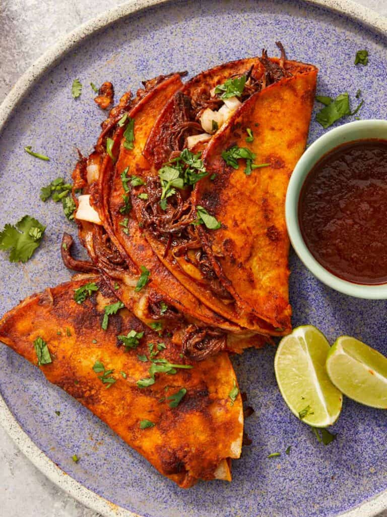 Crispy beef birria tacos with melty cheese and a rich red chile broth for dipping—bold, cheesy, and full of flavor.