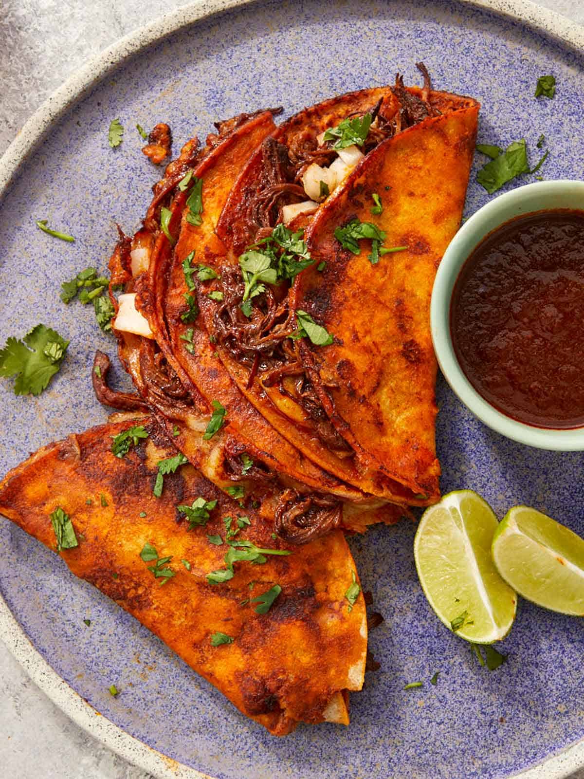 Crispy beef birria tacos with melty cheese and a rich red chile broth for dippingโbold, cheesy, and full of flavor.