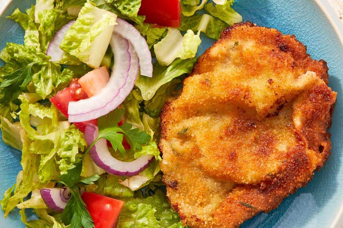 Beef milanesa plated with tomato salad.
