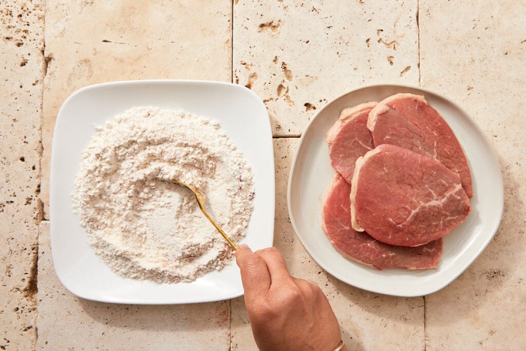 Flour mixed with paprika, salt, pepper, and garlic powder in a shallow bowl