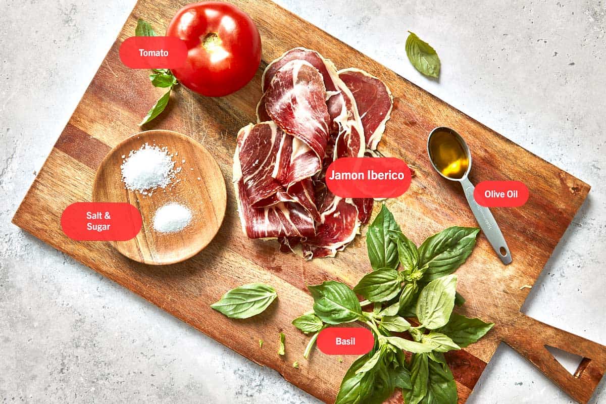Ingredients for Spanish tomato bread laid out on a wooden board.