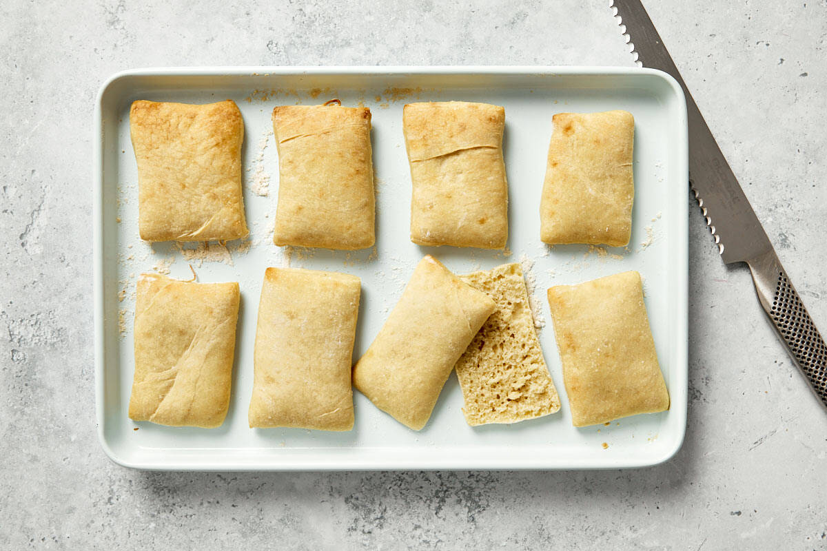 Crispy baked  bread sliced open and rubbed with garlic on a baking tray.