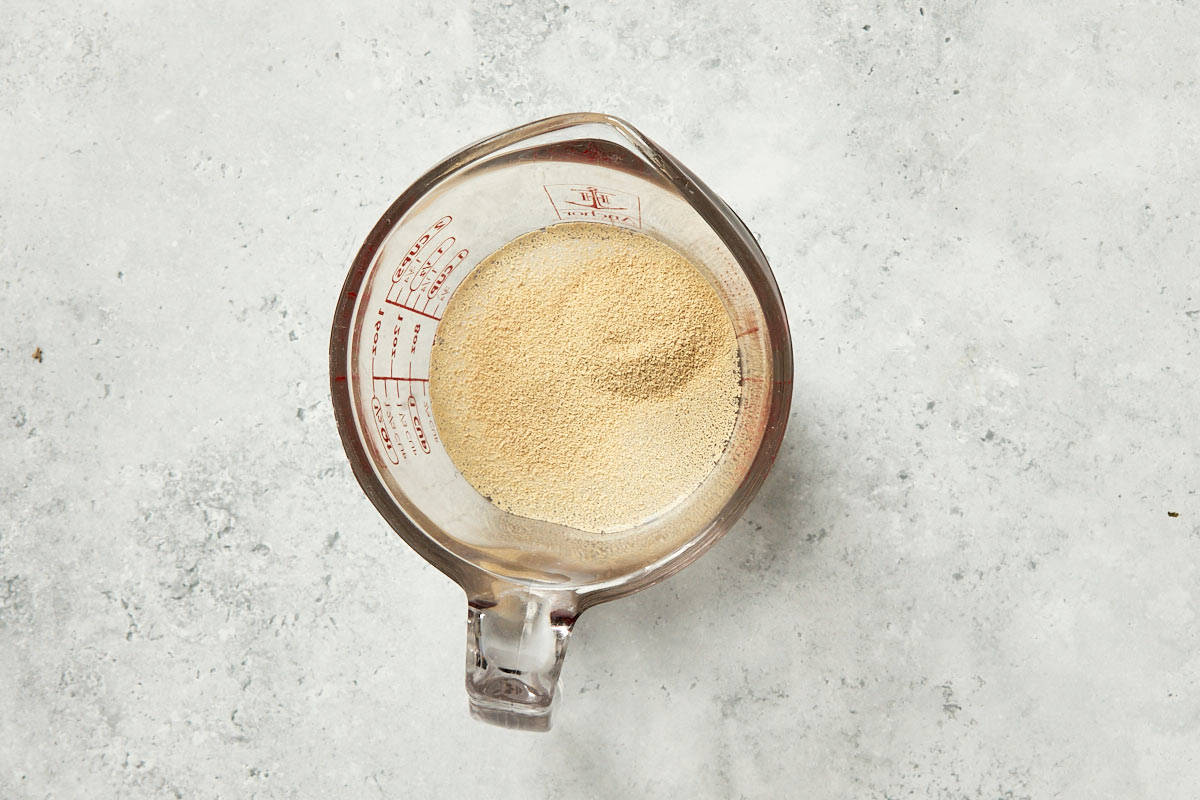 Measuring cup with bubbly active yeast mixture for Spanish tomato bread dough.