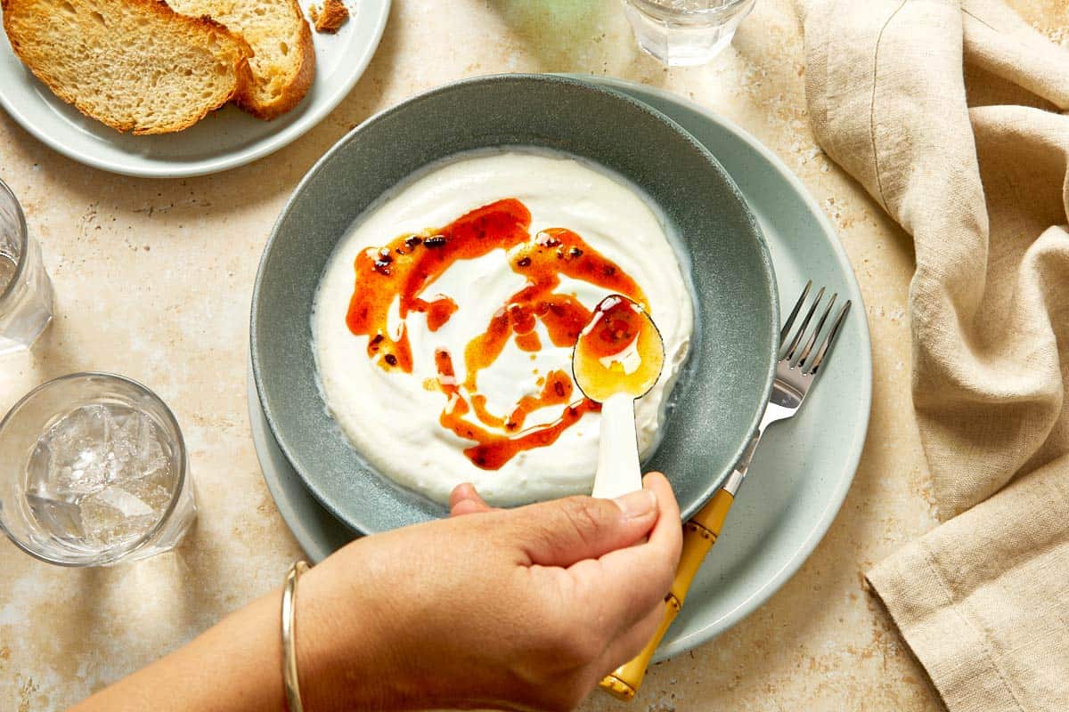 Drizzling chili butter over whipped yogurt.