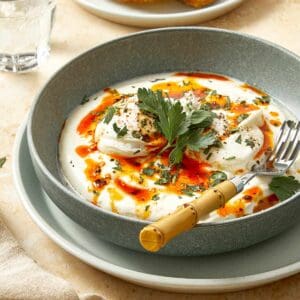 Poached eggs over creamy yogurt with chili butter and herbs, served with crusty bread.