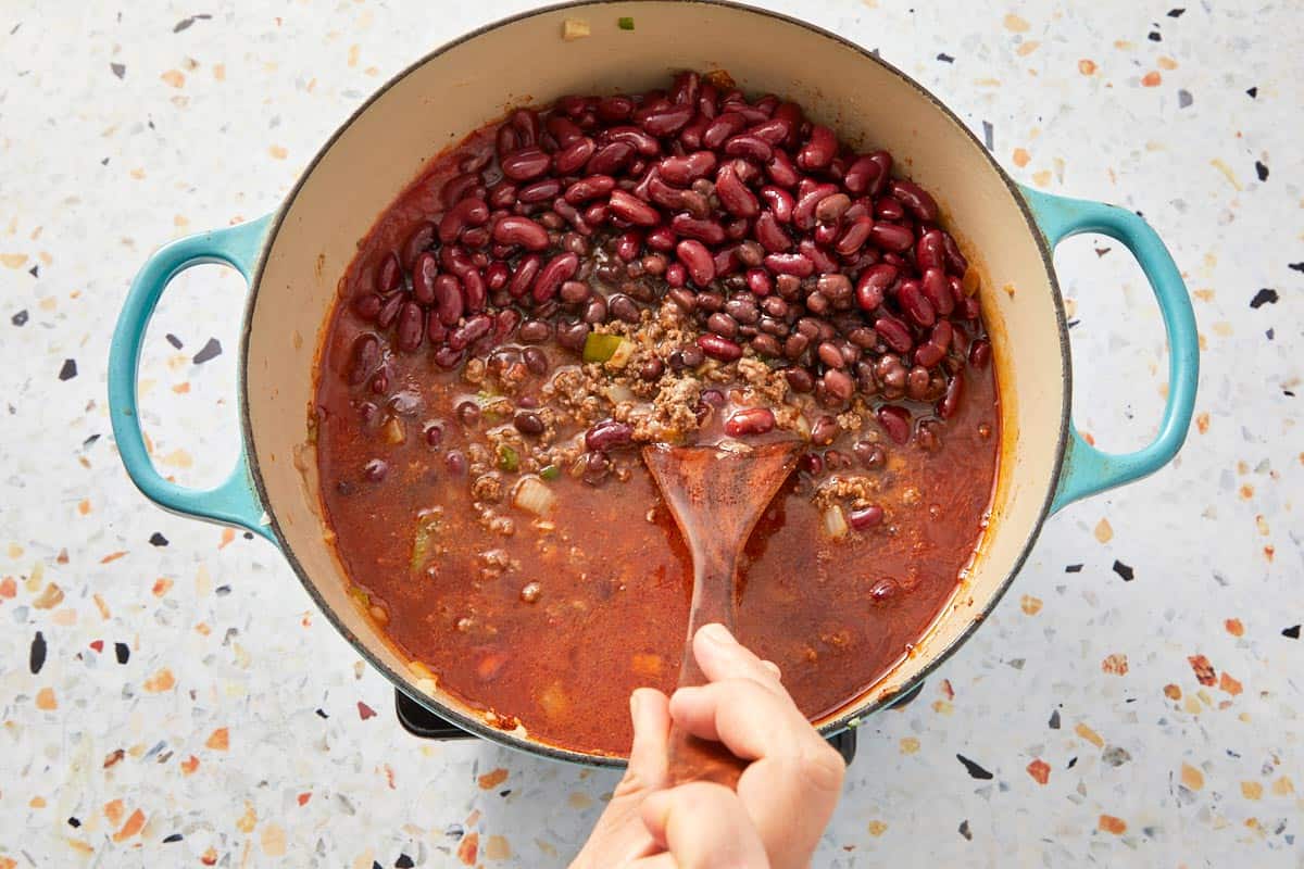Stirring in kidney and black beans into the chili base.