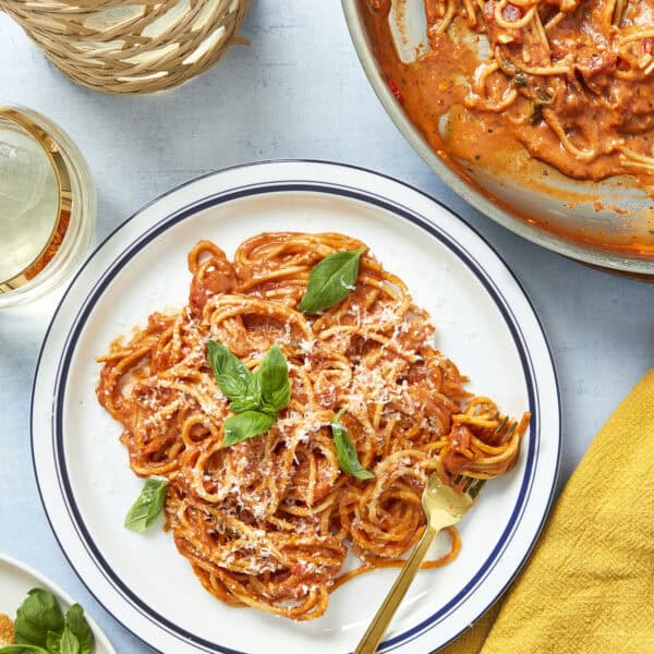 Plate of creamy tomato pasta with fresh basil and parmesan served in a white dish.