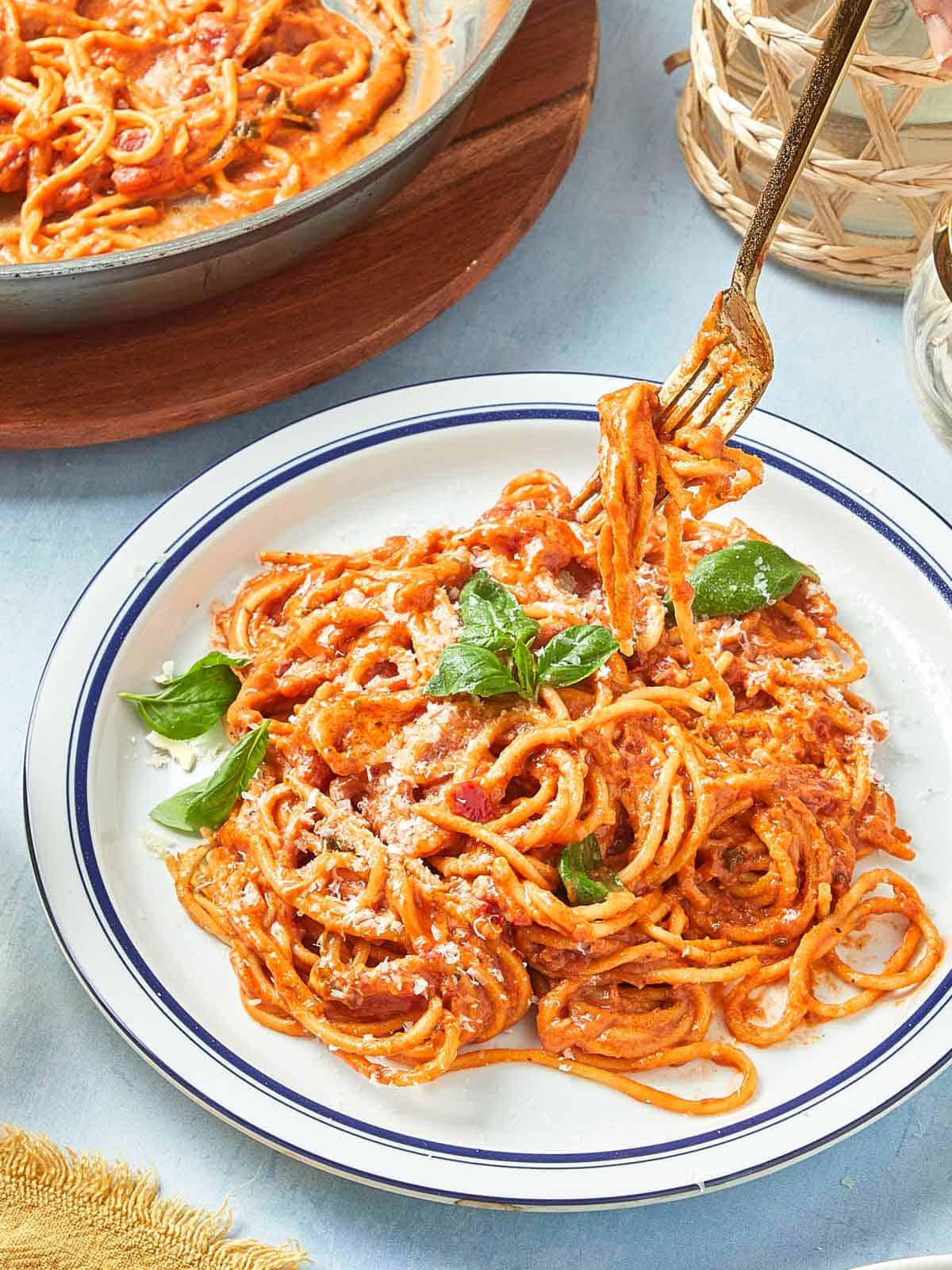 Plate of creamy tomato pasta with fresh basil and parmesan served in a white dish.