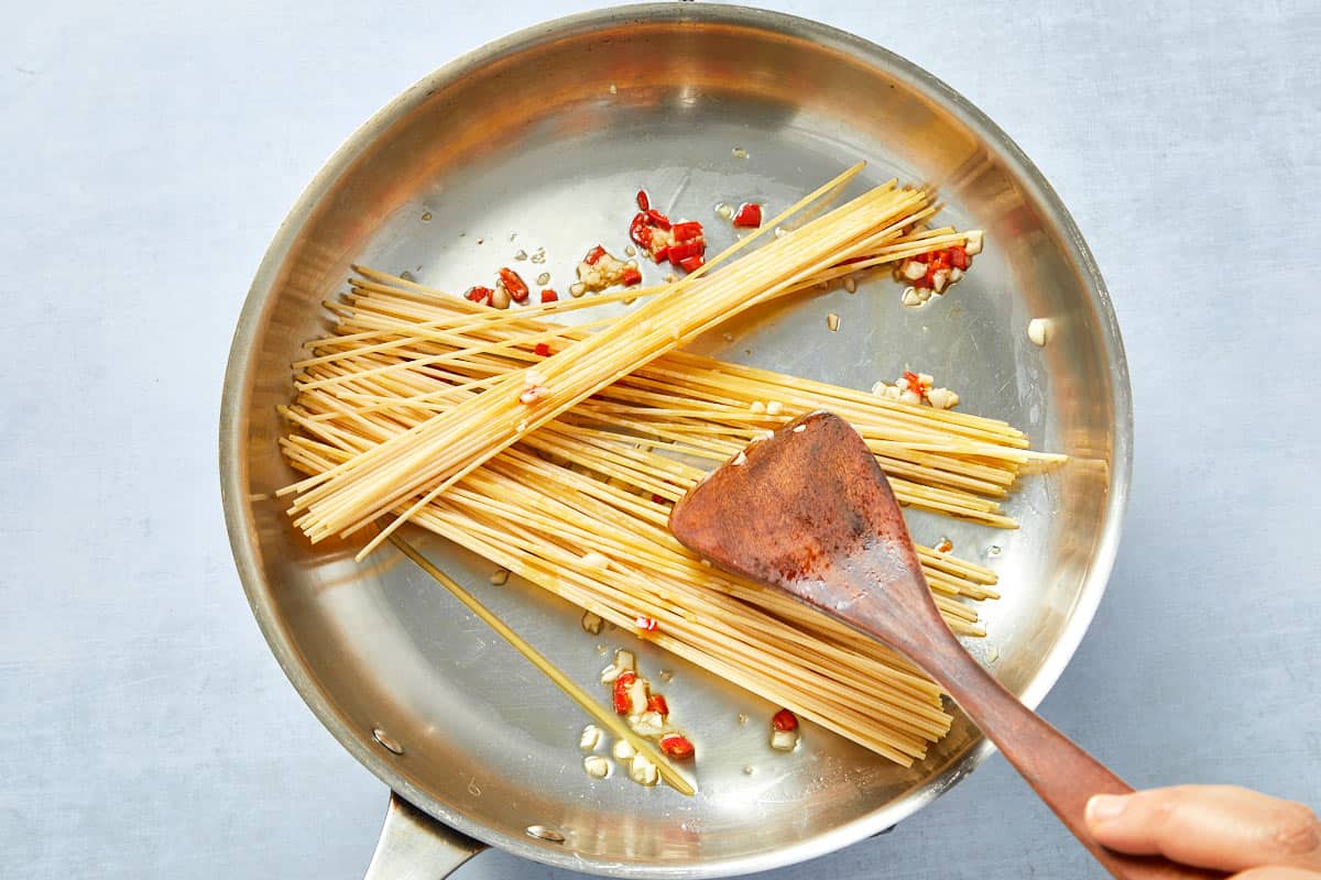 Dry spaghetti added to the garlic and chili oil.