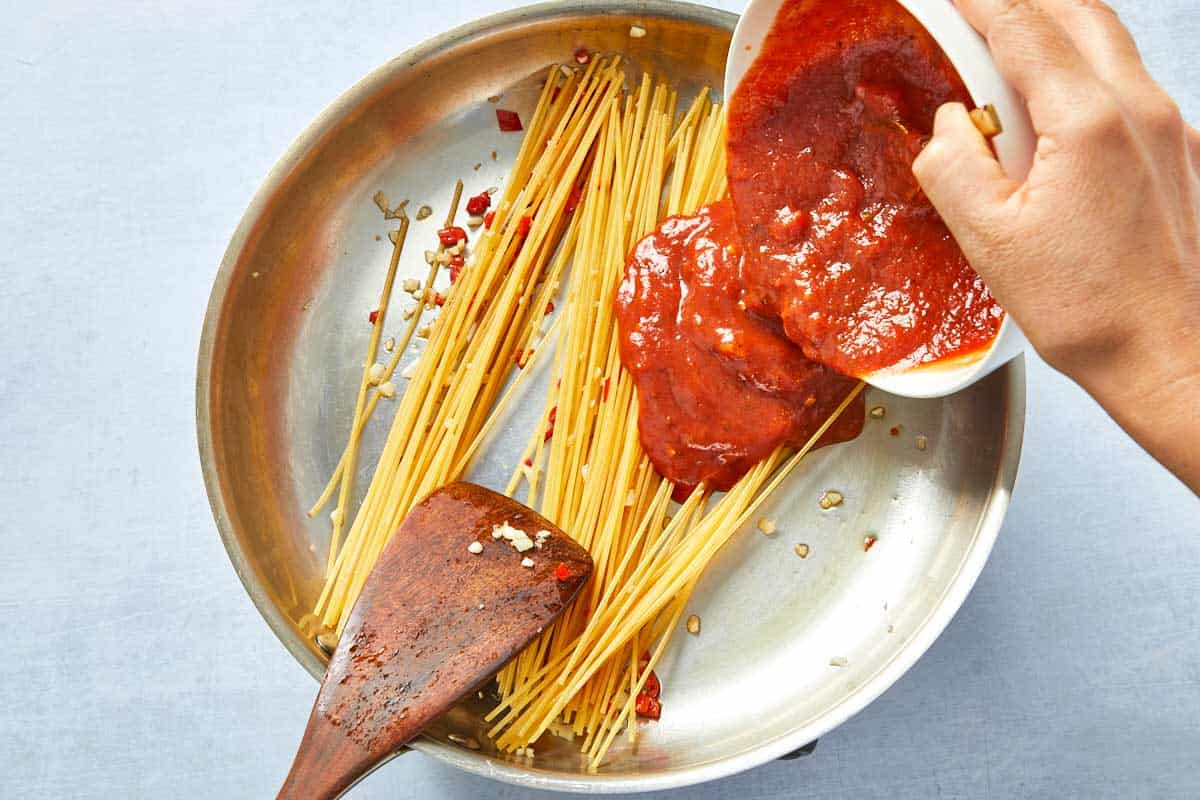Pomodoro sauce poured over pasta in the pan.