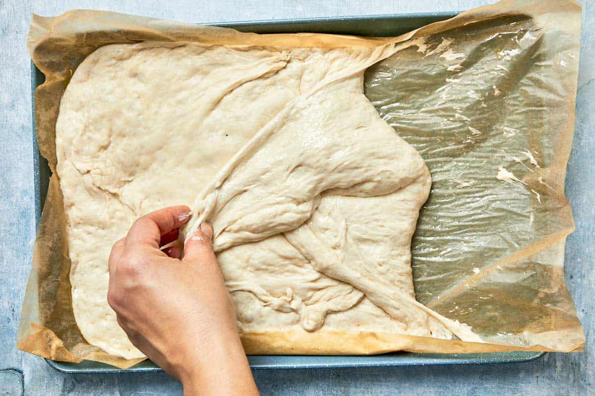 Dough being gently folded from the sides after rising.