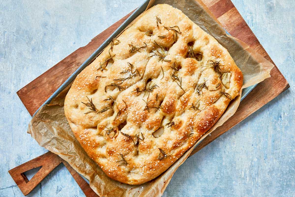 Golden-brown baked focaccia fresh out of the oven, topped with rosemary.