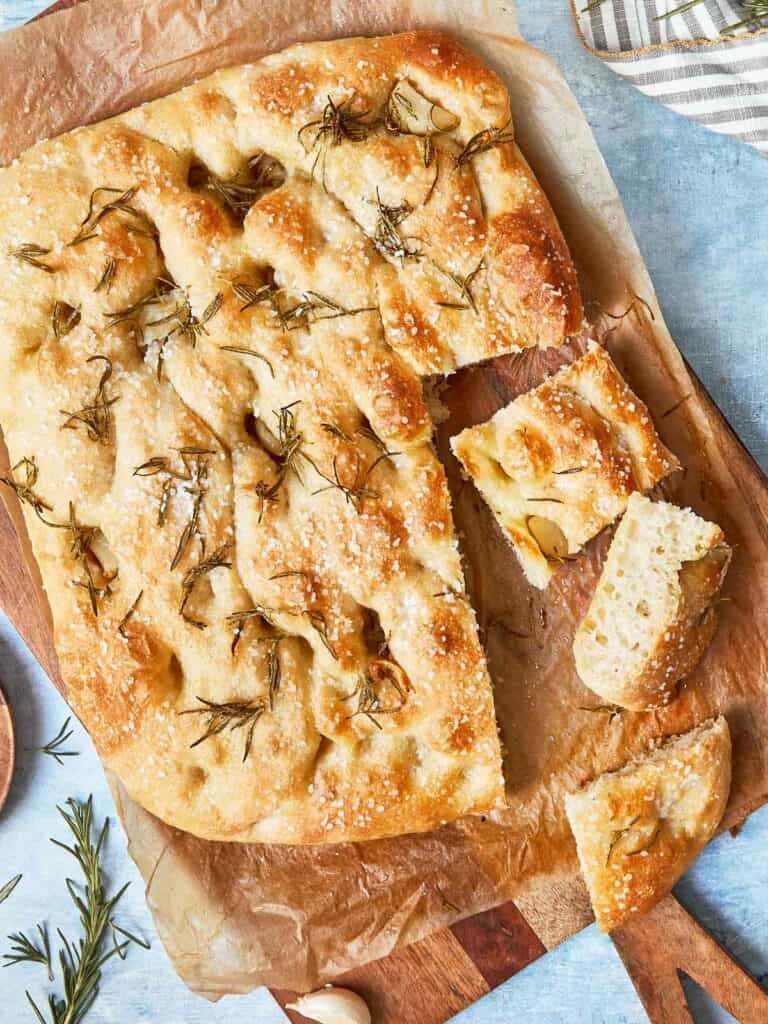 Sliced focaccia showing airy texture, crispy edges, and rosemary on top.