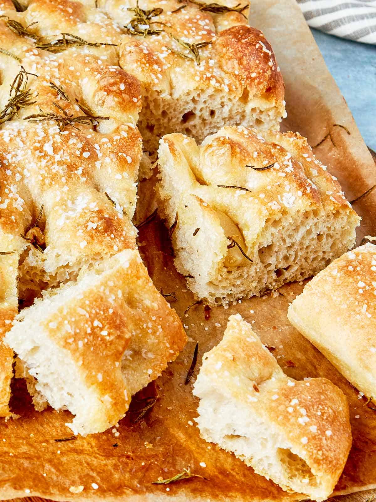 Close-up of sliced focaccia showing airy texture, crispy edges, and rosemary on top.