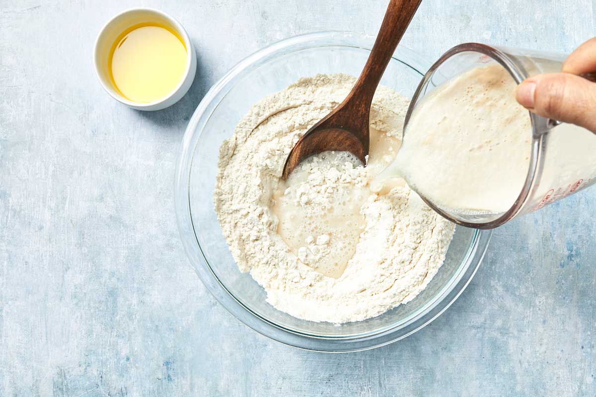Yeast mixture being poured into flour to form dough.