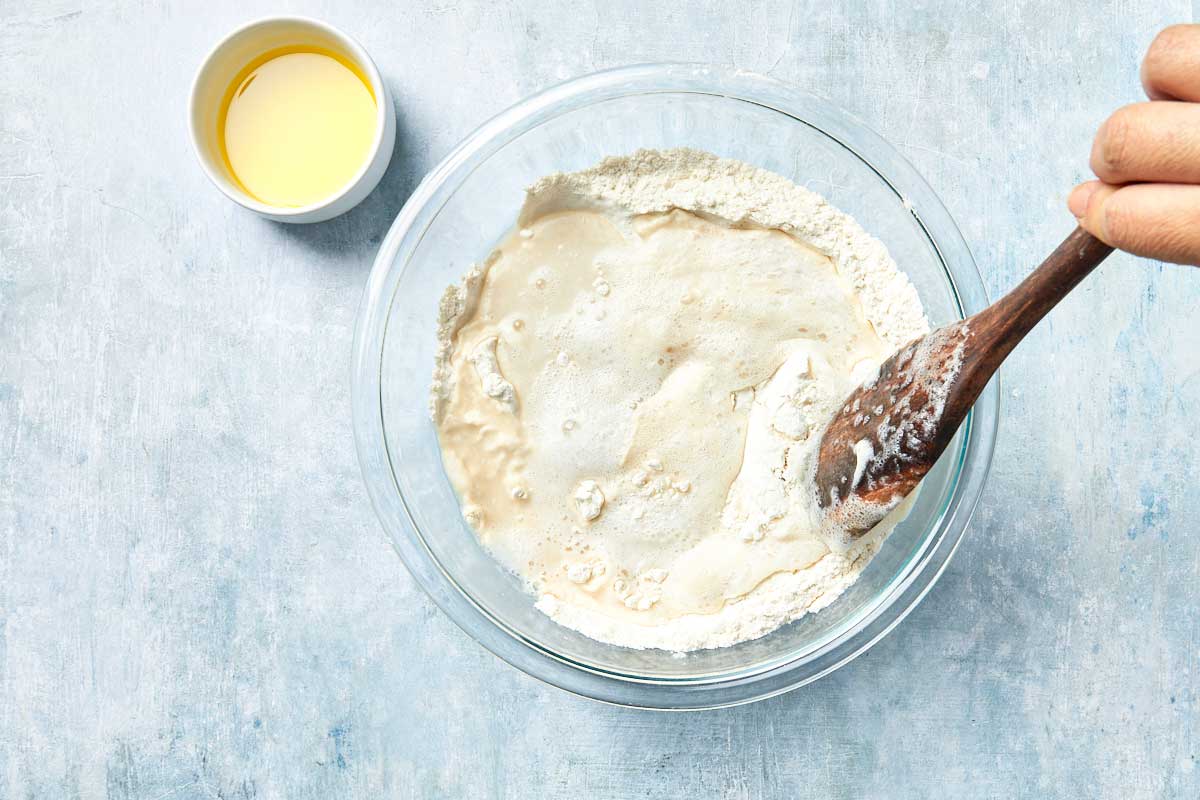Mixing yeast and flour in a bowl with a wooden spoon.