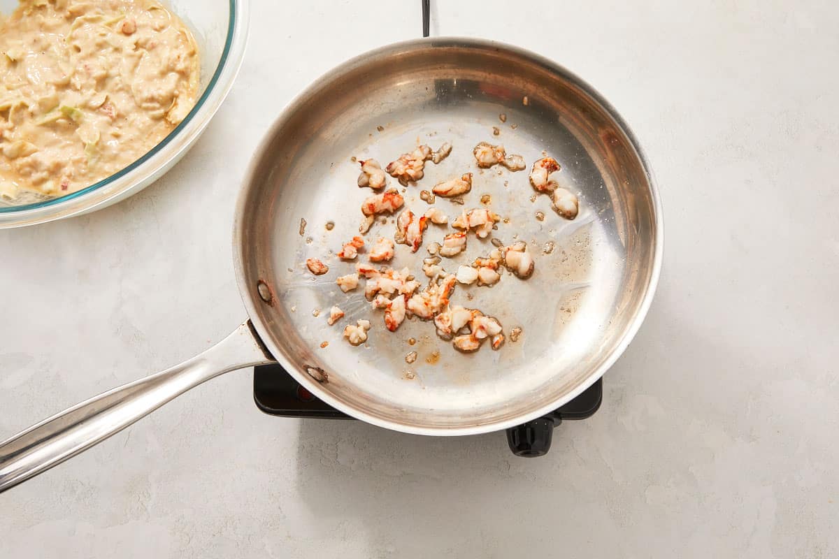 Chopped shrimp cooking in a lightly oiled pan over a burner.