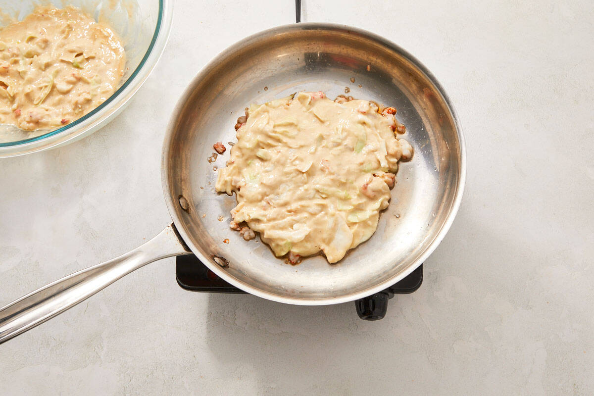 Thick batter poured into the pan over the cooked shrimp, shaped into a circle.
