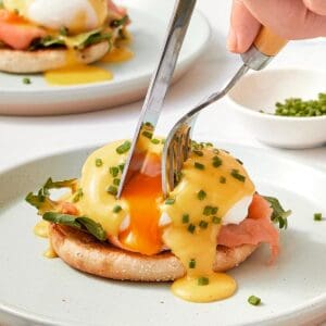 A person cutting a piece of egg on a plate.